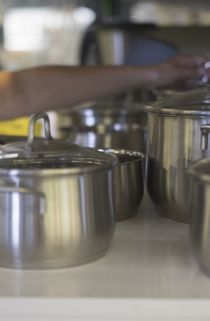 caucasian lady choose new pot for home in a big store with a lot of variety