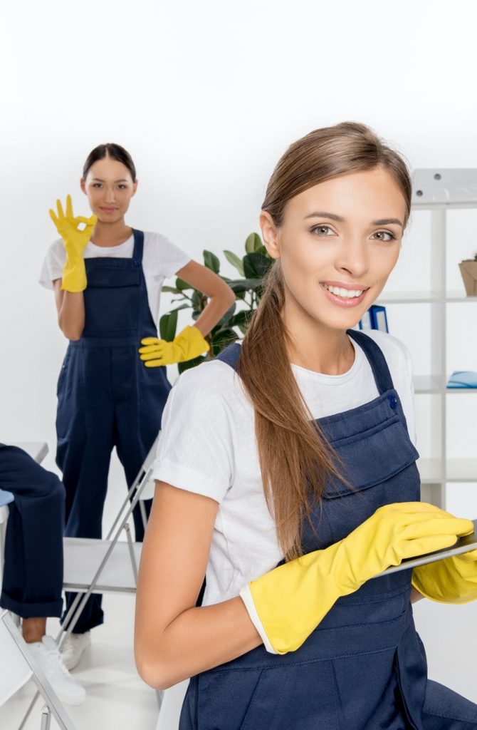 smiling-young-female-cleaner-using-digital-tablet-while-colleagues-working-behind.jpg